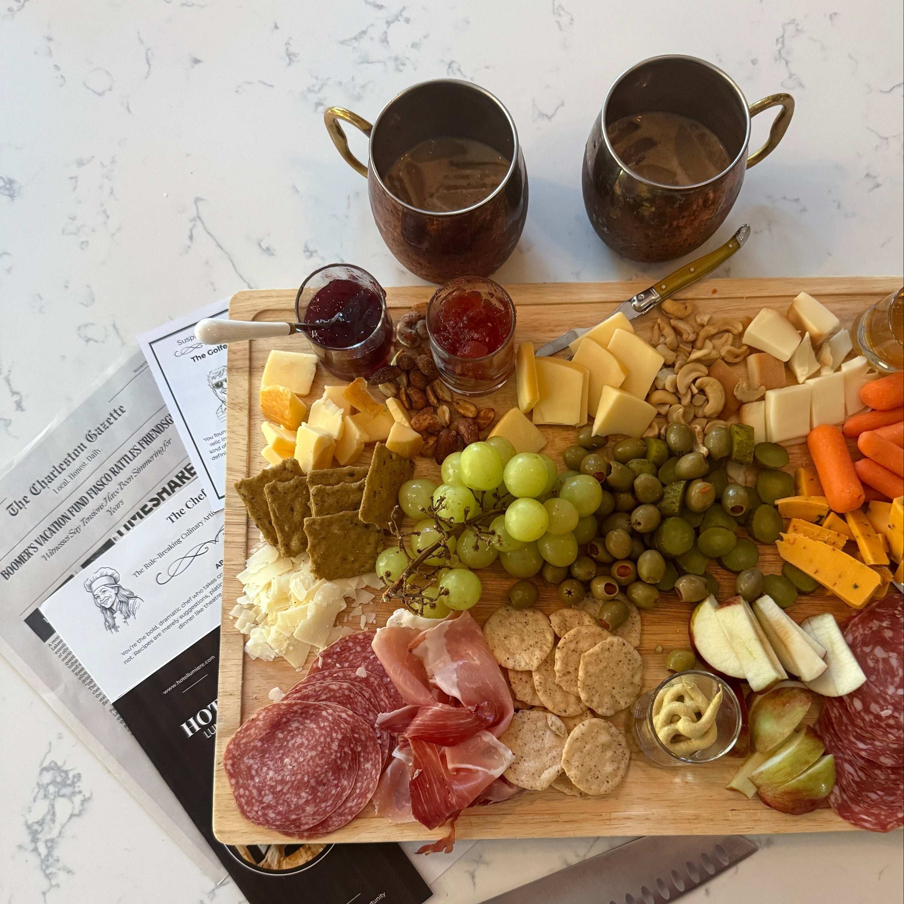Charcuterie board with meats, cheeses, and fruits on a marble surface.